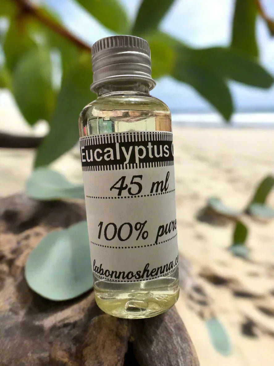 45 ml glass bottle of 100% pure eucalyptus oil on wood, leaves and beach background