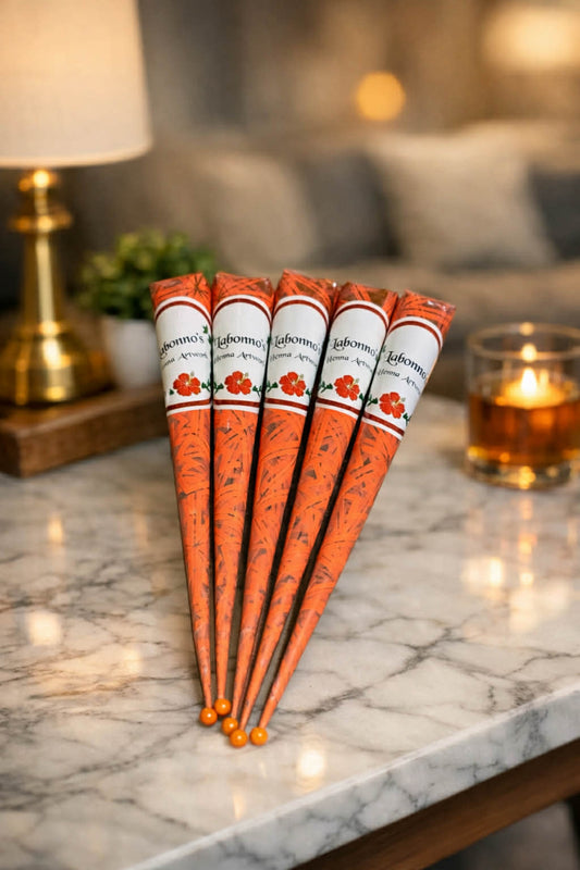 Five henna cones on a marble table, ideal for mehndi tattoo designs in a cozy indoor setting.