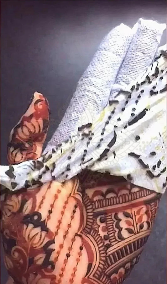 Hand with intricate henna artwork, partial tissue wrap, rich floral and geometric mehndi design.