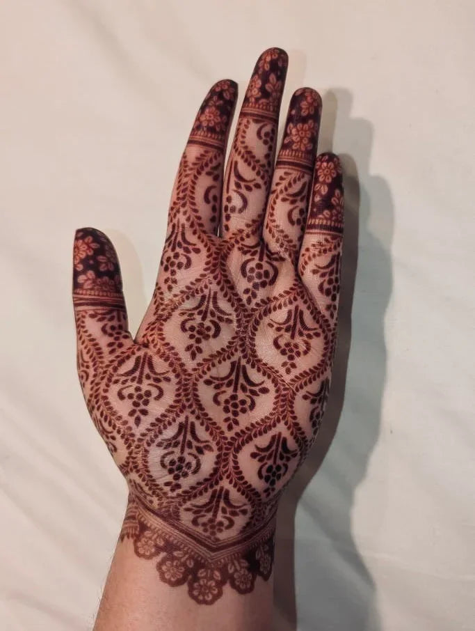 Hand with intricate henna artwork featuring floral and paisley patterns on palm and fingers