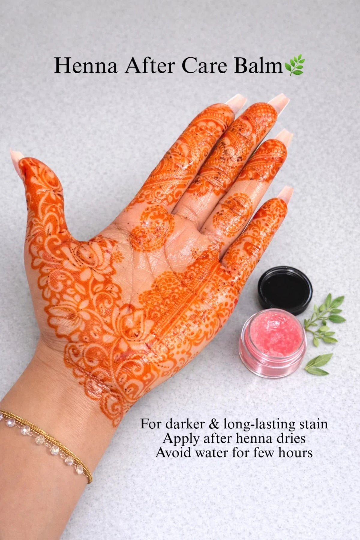Henna decorated hand with aftercare balm jar, instructions for darker, long-lasting stain.