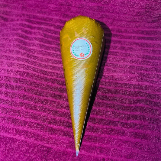 Henna cone with a label on a textured purple background, natural dye body art product.