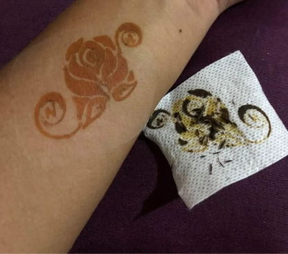 Henna rose design on forearm with peeled stencil on tissue, body art closeup