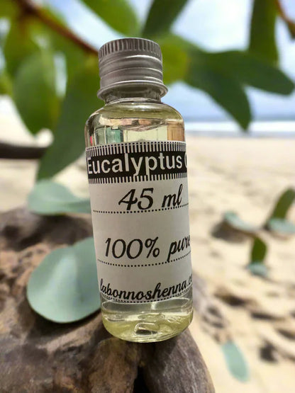 45 ml glass bottle of 100% pure eucalyptus oil on wood, leaves and beach background