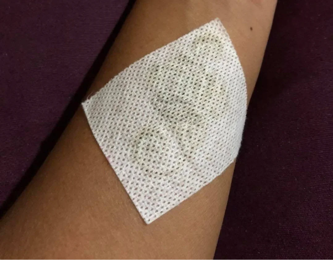 Arm with a white gauze bandage covering a henna tattoo, close-up shot.