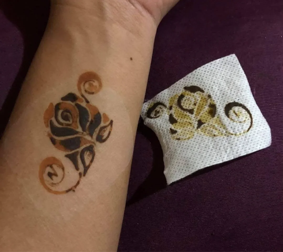 Floral henna design on forearm with matching pattern on tissue, intricate body art.