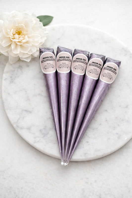 Five metallic purple jagua gel cones for body art on a marble plate with a white flower.
