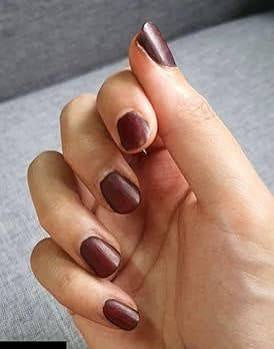 Hand with matte brown henna-stained nails displayed on a neutral background
